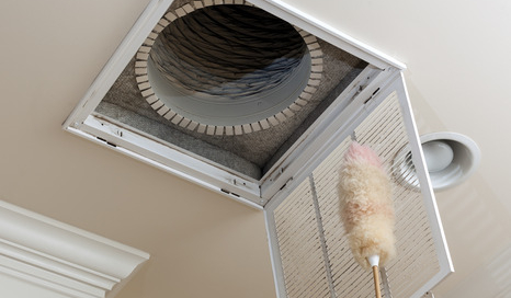 Dusting the vent for air conditioning filter in ceiling of modern home